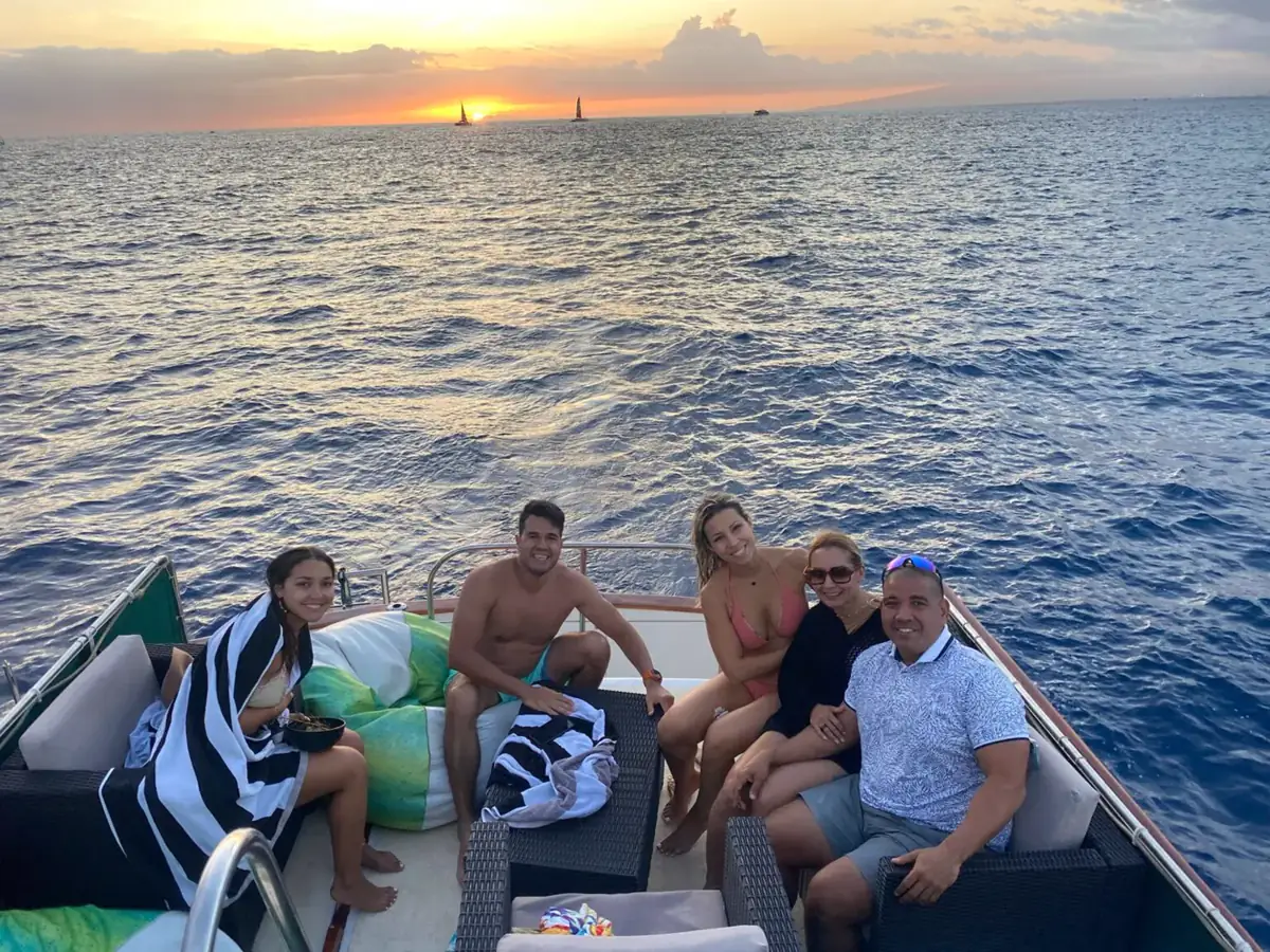 A small group of guests relaxing on the Kona Star deck at sunset off Waikiki