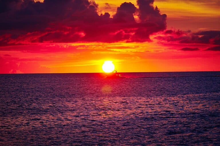 A boat on the water in the sunset.