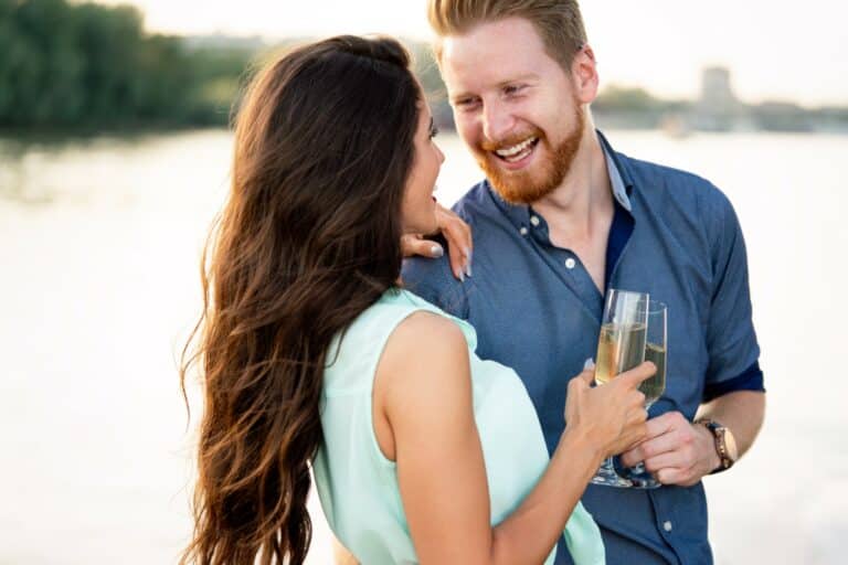 A happy couple smiling and drinking champagne together on a boat.